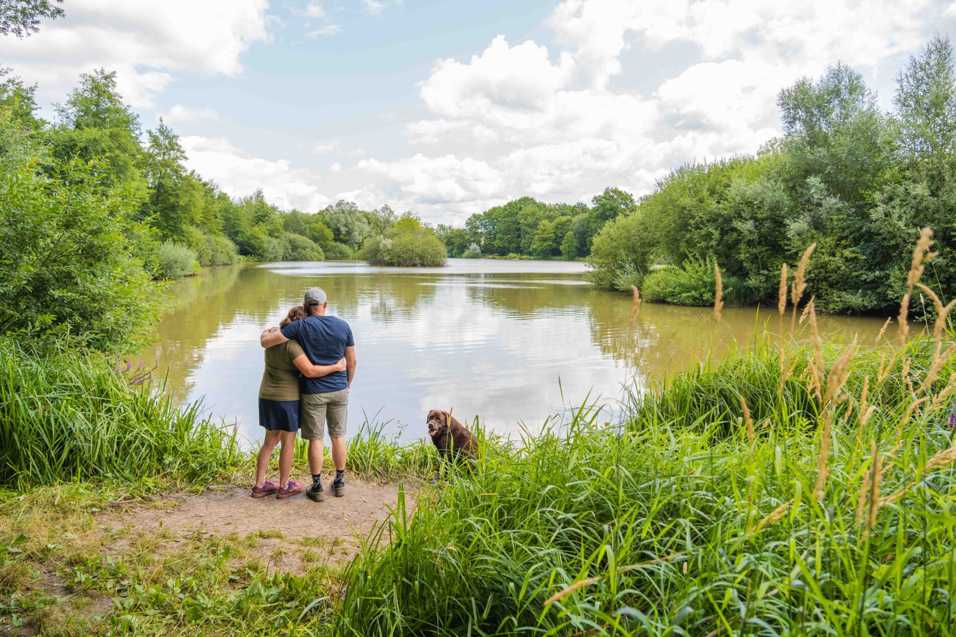 Balade en couple avec un chien face à l'étang de Breuillez à Bremondans.